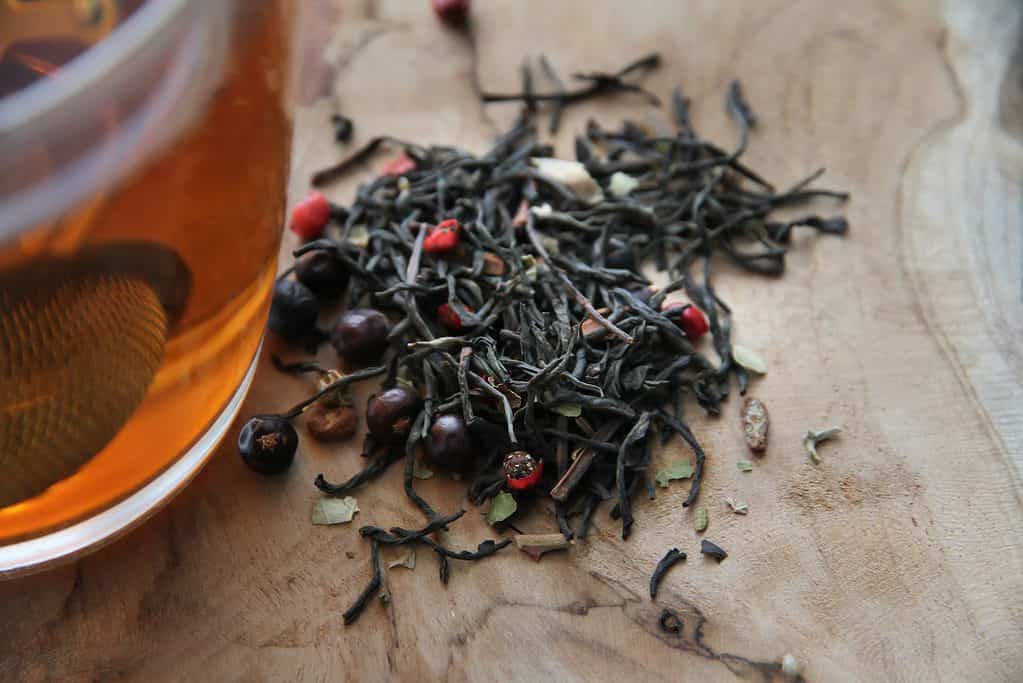 red and black round fruit on brown wooden table, bringing loose leaf tea on a plane